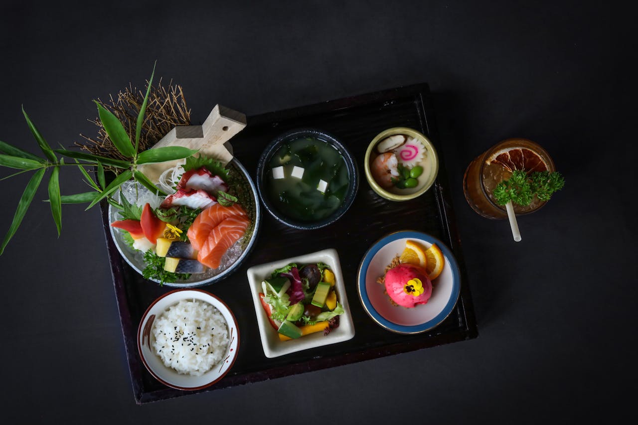 services-05 A vibrant display of Japanese dishes including sashimi, salad, and dessert.