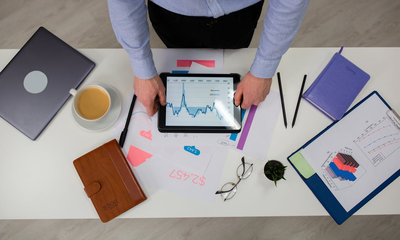 our-story Overhead view of businessman using tablet to review data charts at a modern office desk.