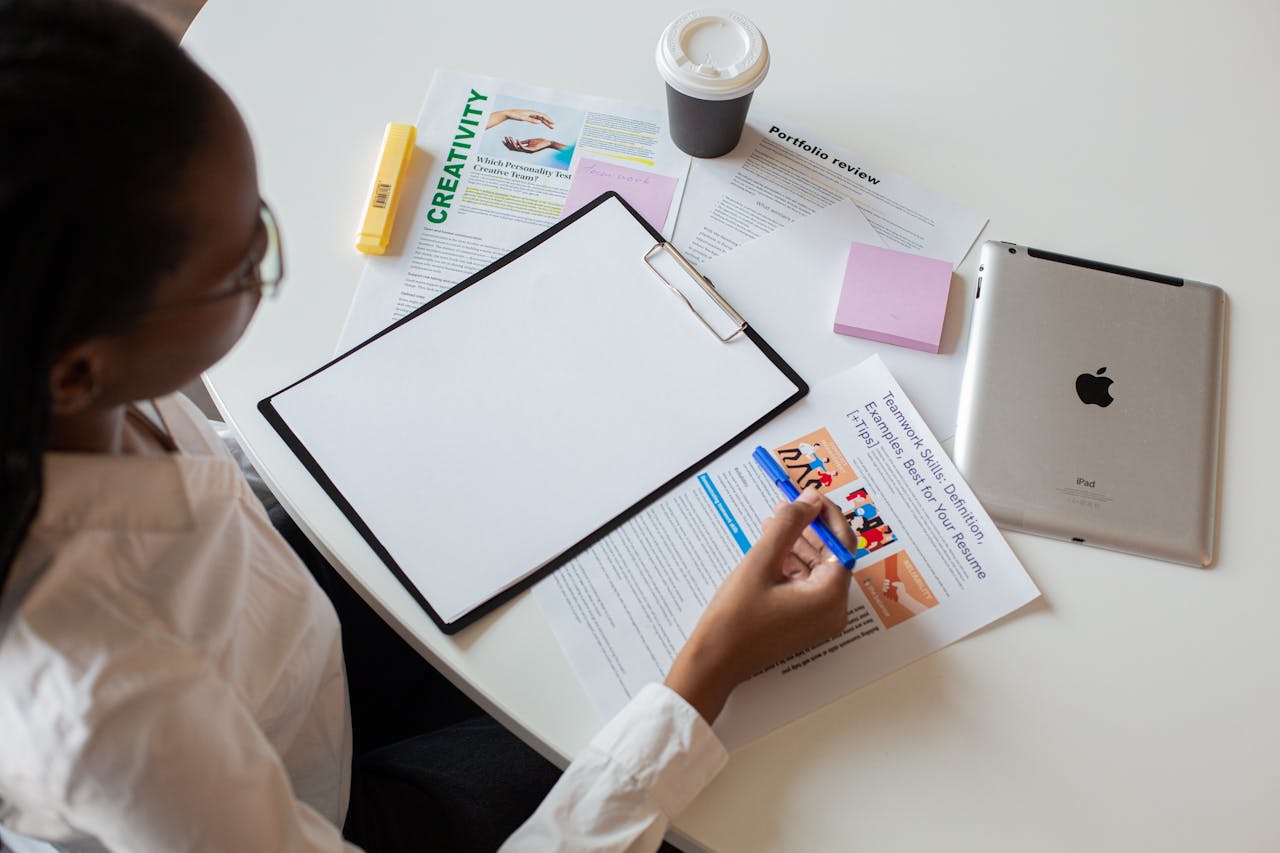 who-we-are Top view of a woman reviewing various documents with a clipboard on a desk.